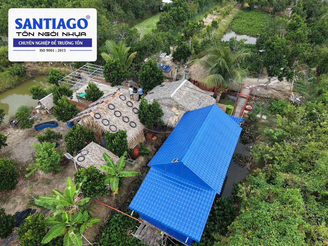 Nhà mái tôn nhựa xanh dương giữa vườn cây nhìn từ flycam