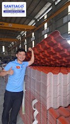 Nhân viên Santiago đứng cạnh chồng ngói nhựa đỏ trong xưởng